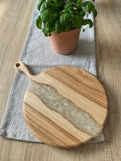 a wooden cutting board sitting on top of a table next to a potted plant