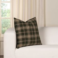 a black and white plaid pillow sitting on top of a couch next to a window