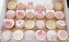 a box filled with lots of pink and white cupcakes