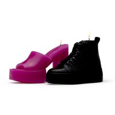 a pair of black and pink shoes with candles in the middle on a white background