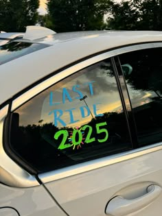 a car with the words last ride written on it's side window, in front of some trees