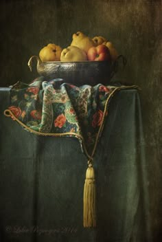 a painting of apples and pears in a bowl on a table cloth with a tassel