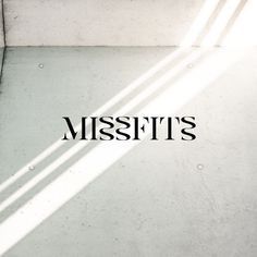 the word missfits written in black ink on a white wall with sunlight coming through it