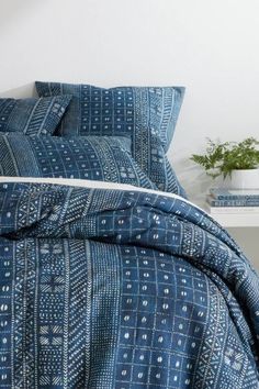 a bed with blue and white bedspread next to a plant on a table