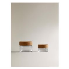 two glass jars with wooden lids sit side by side