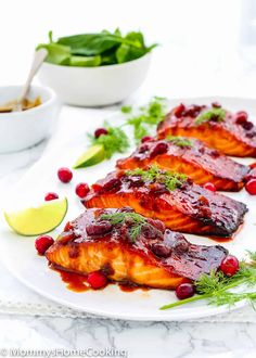 three salmon fillets with cranberry sauce and garnish on a white plate