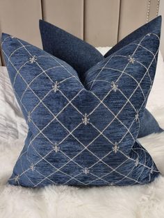 two blue pillows sitting on top of a white bed