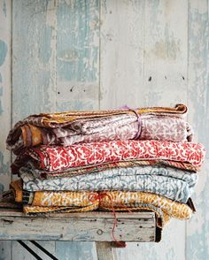 a stack of cloths sitting on top of a wooden table next to a wall