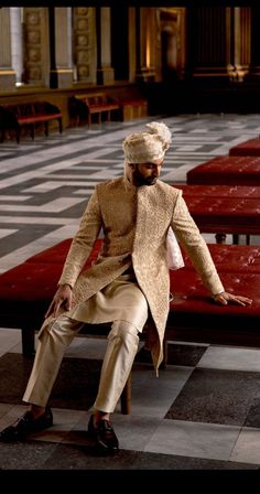 a man in a turban sitting on a bench with his hands out to the side