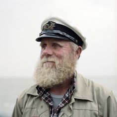 an old man with a beard wearing a sailor's hat and looking off into the distance