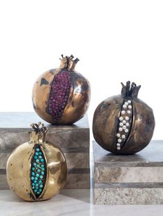 three pomegranates with beads on them sitting on top of marble blocks