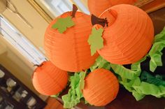 some paper pumpkins are sitting on top of green lettuce and leaves in front of a window