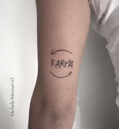 a person with a tattoo on their arm and the word karma written in black ink