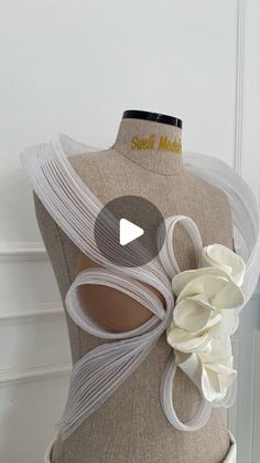 a mannequin with white ribbons and flowers on it