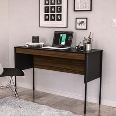 a desk with a laptop and other items on it next to a chair in a room