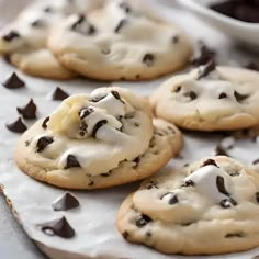 cookies with chocolate chips and white icing on a baking sheet, ready to be eaten