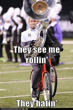 a man on a bike with a trumpet in his mouth and the words they see me rollin '