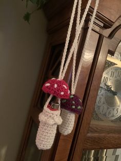 two crocheted mushrooms hanging from the side of a grandfather clock