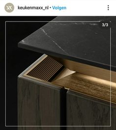 an open book on top of a wooden cabinet with black marble and gold trimmings