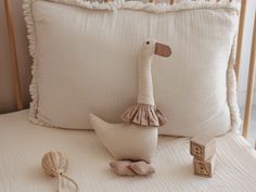 a stuffed duck sitting on top of a bed next to a pillow and wooden blocks