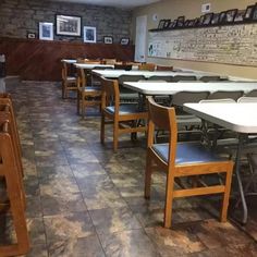 tables and chairs are lined up in the dining room at an empty restaurant with brick walls