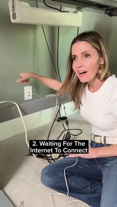 a woman is sitting on the floor with her hand out and pointing at something in front of her