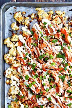 a tray filled with cauliflower covered in ranch dressing and topped with green onions