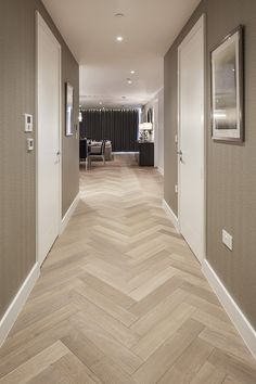 a long hallway with wood flooring and white trim on the walls, leading to a dining room