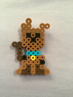 a brown bear made out of wooden pegs sitting on top of a white surface