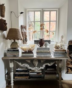 a table with books and vases on it in front of a window