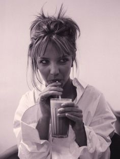 a black and white photo of a woman drinking from a cup with an instagramr