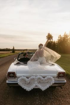 a bride and groom in their wedding car on the side of the road at sunset