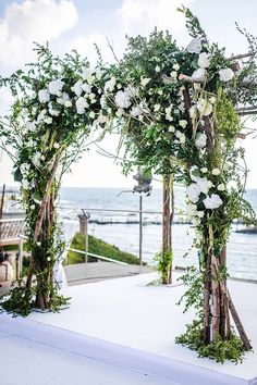 an outdoor ceremony setup with white flowers and greenery