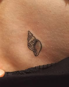 a woman's stomach with a small shell tattoo on it