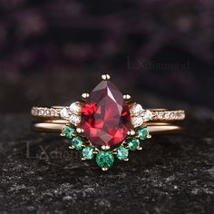 a close up of a ring with a red and green stone in the center on a black surface