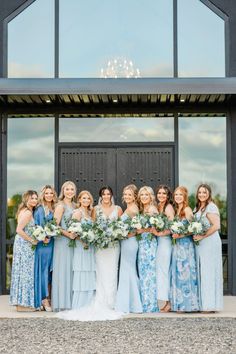 a group of women standing next to each other in front of a black door holding bouquets