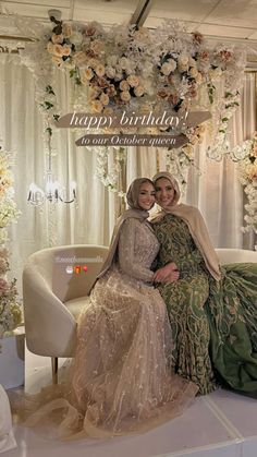 two women are sitting on a couch in front of a floral decorated birthday card that says happy birthday