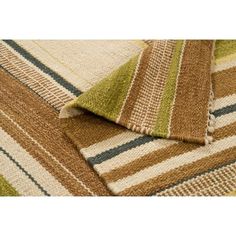 a multicolored striped rug is folded on top of the floor, with an area rug underneath it