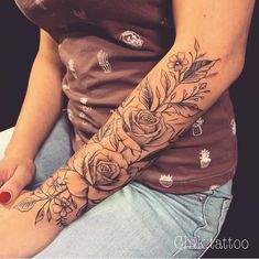 a woman's arm with flowers and leaves on her left arm, while sitting down