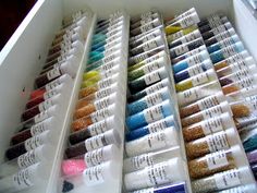 many colors of nail polish are on display in a white box with clear plastic dividers