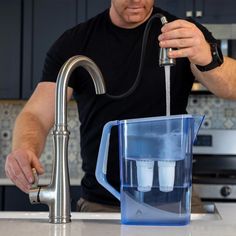 a man is pouring water into a blender in the kitchen with his hand on the faucet