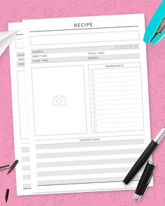 a recipe book on top of a pink surface with pens and paper clips next to it