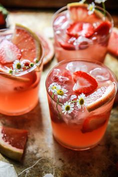 two glasses filled with watermelon and strawberries next to slices of grapefruit