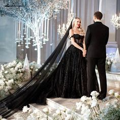 a man and woman standing next to each other in front of a stage with chandeliers