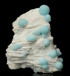 a white rock with some blue balls on it's side and black back ground