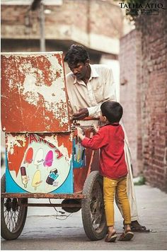 an old man pushing a cart with a young boy on the front and back wheels