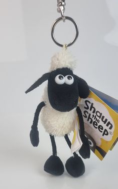 a black and white sheep keychain with a snack bag in it's mouth