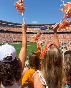 two girls are holding up some food in the air at an orange and white football game