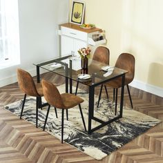 a dining room table with four chairs and a rug on the floor in front of it