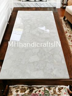 a white marble table top sitting on top of a wooden floor next to a couch